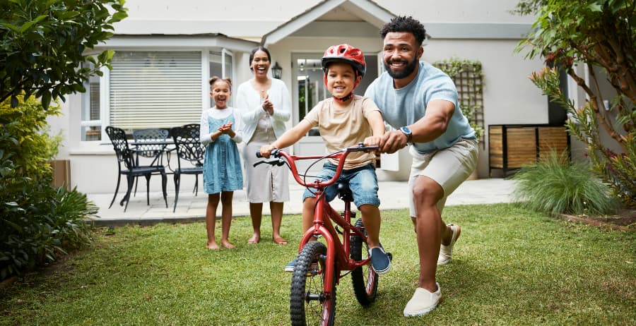 Kid learning to ride a bike at his home with family
